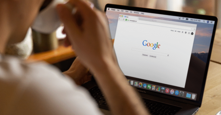 View from behind of a person drinking a cup of coffee at a desk performing a Google Search.